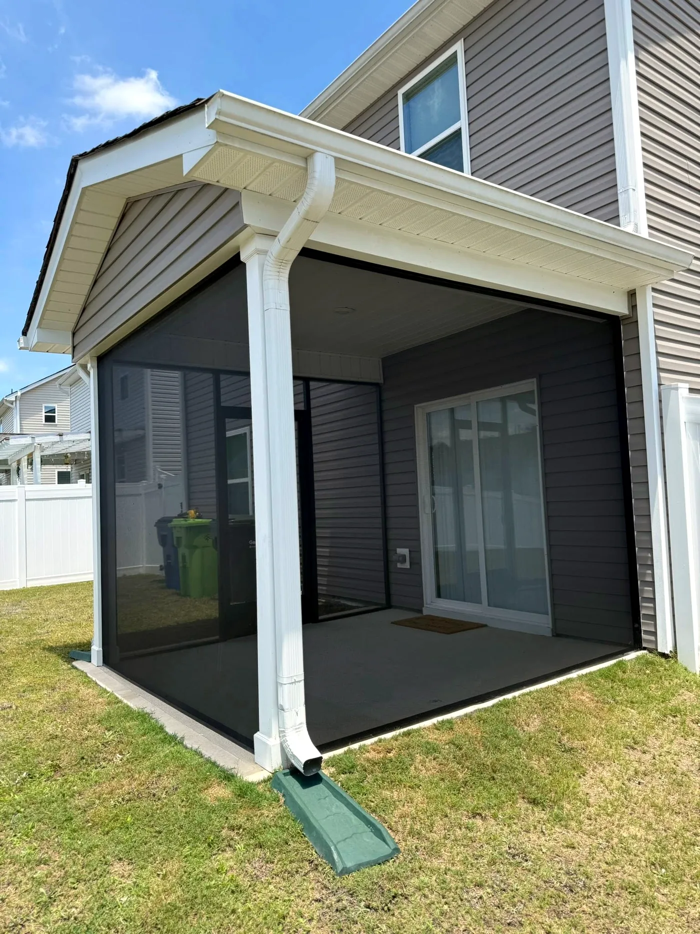 Small covered patio screened in with black mesh panels and white trim