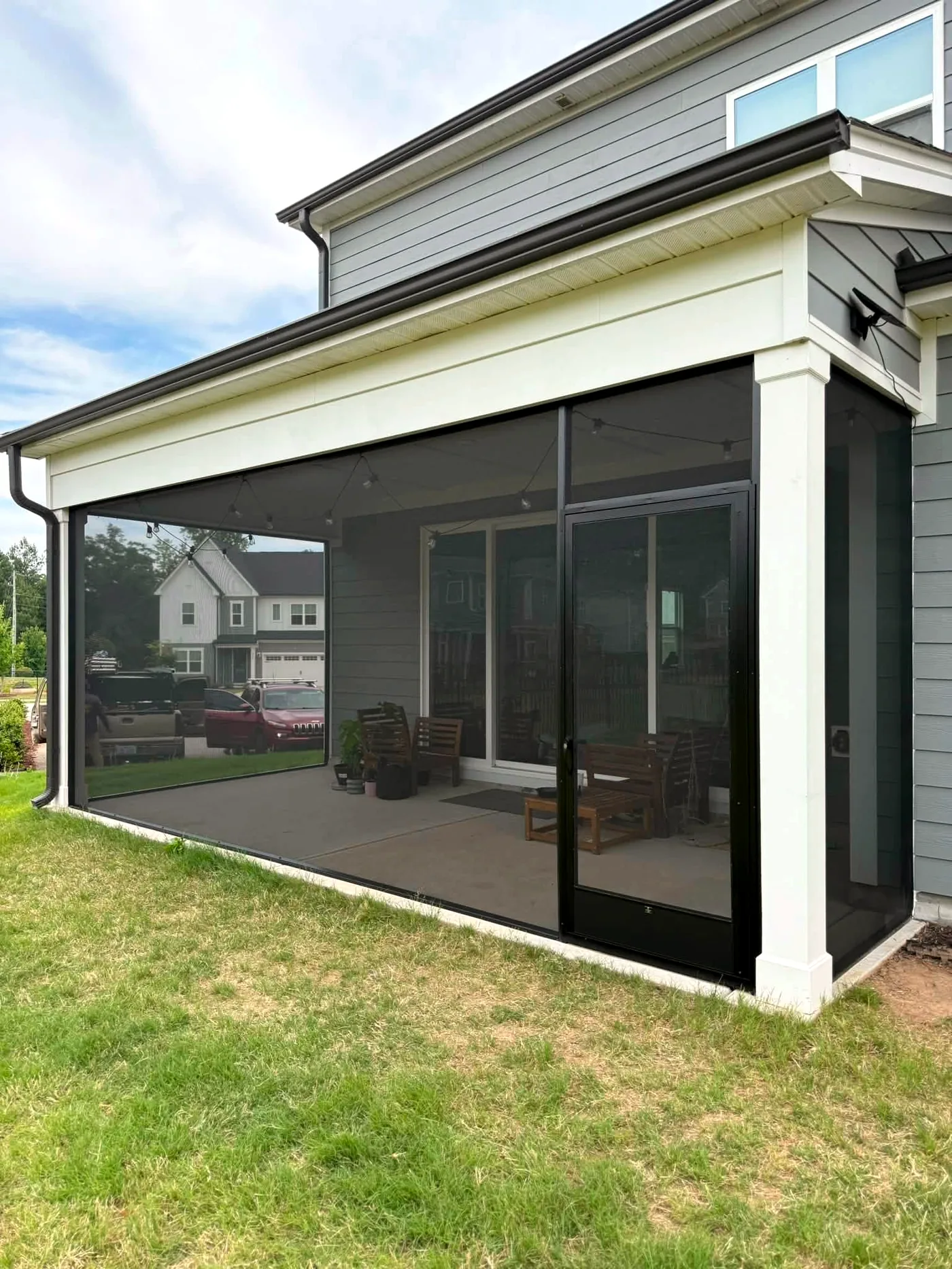 Covered concrete patio screened in with black screen panels and a screen door